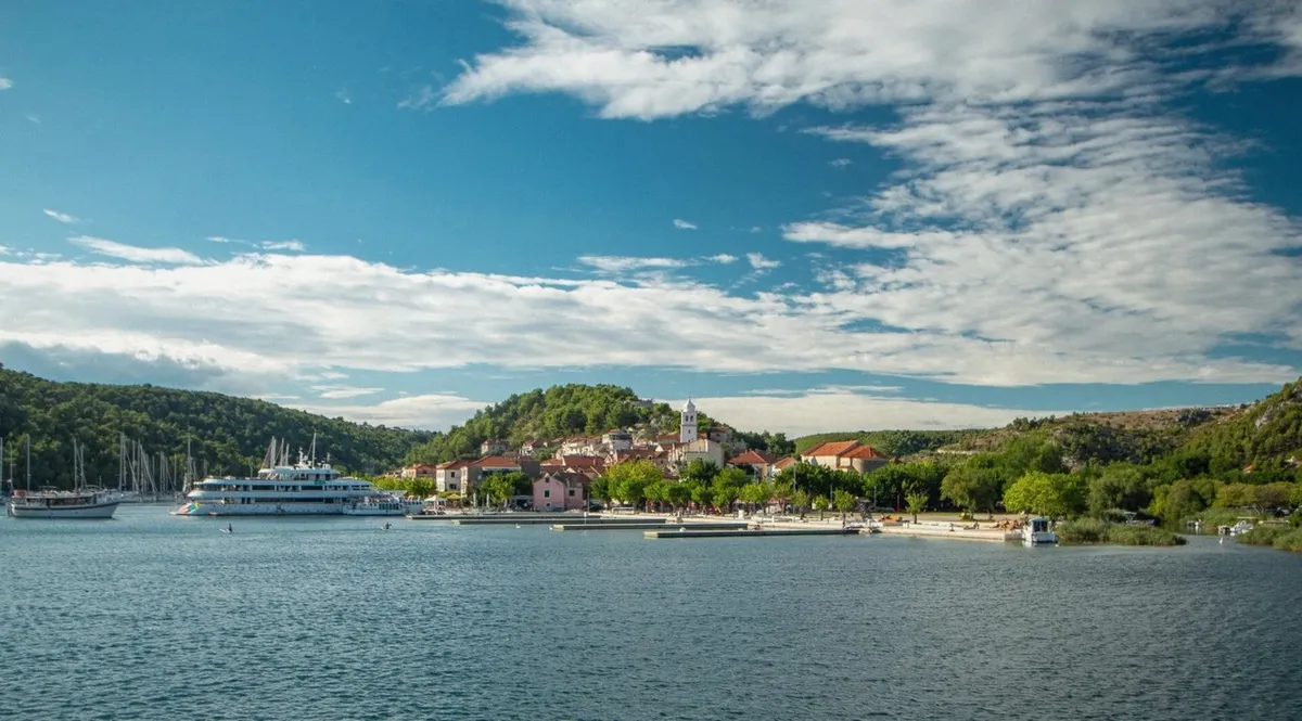 Coach on the Dalmatian coast road from Split towards Krka National Park with green hills and the Adriatic in view on a Split to Krka day trip